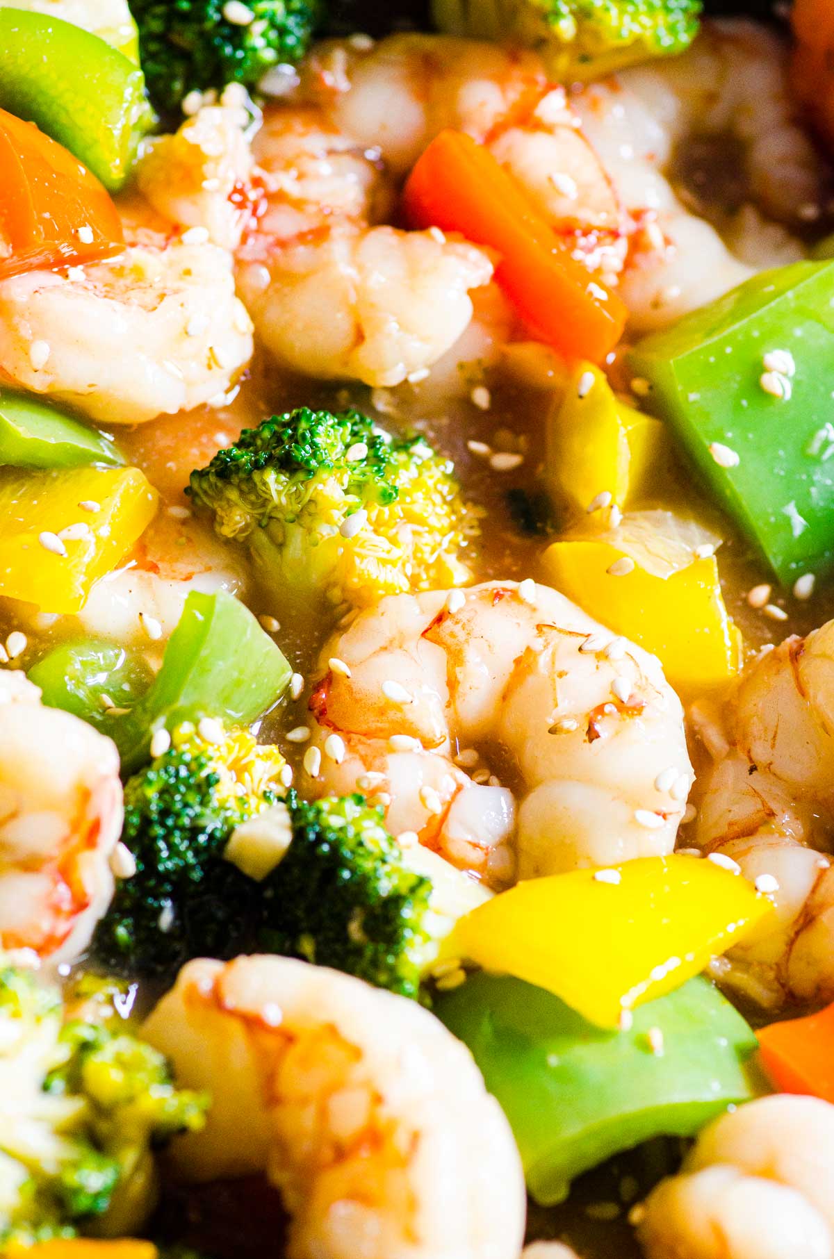 shrimp with broccoli and bell peppers in a sauce sprinkled with sesame seeds