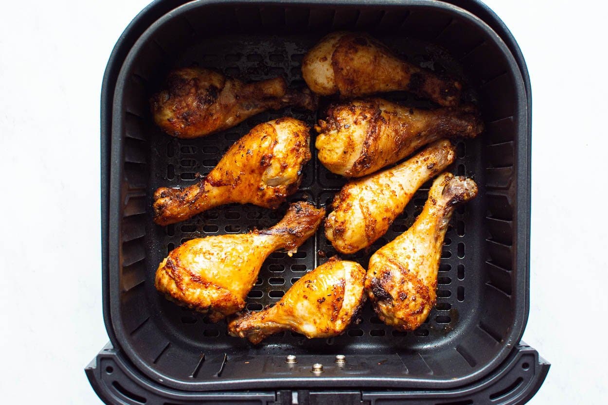 Cooked drumsticks in air fryer basket.