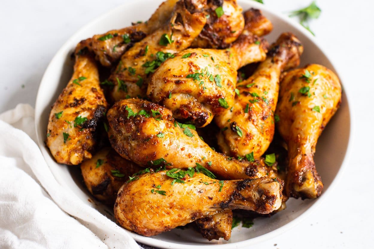 Air fried chicken drumsticks on a plate with garnish and a linen napkin.