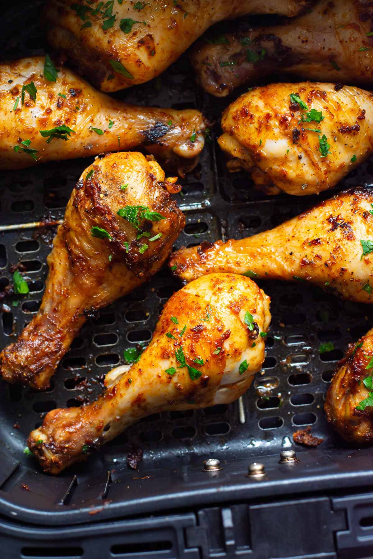 Air fryer chicken drumsticks garnished with seasoning and parsley.