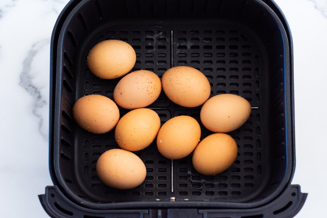 Brown eggs in an air fryer basket.
