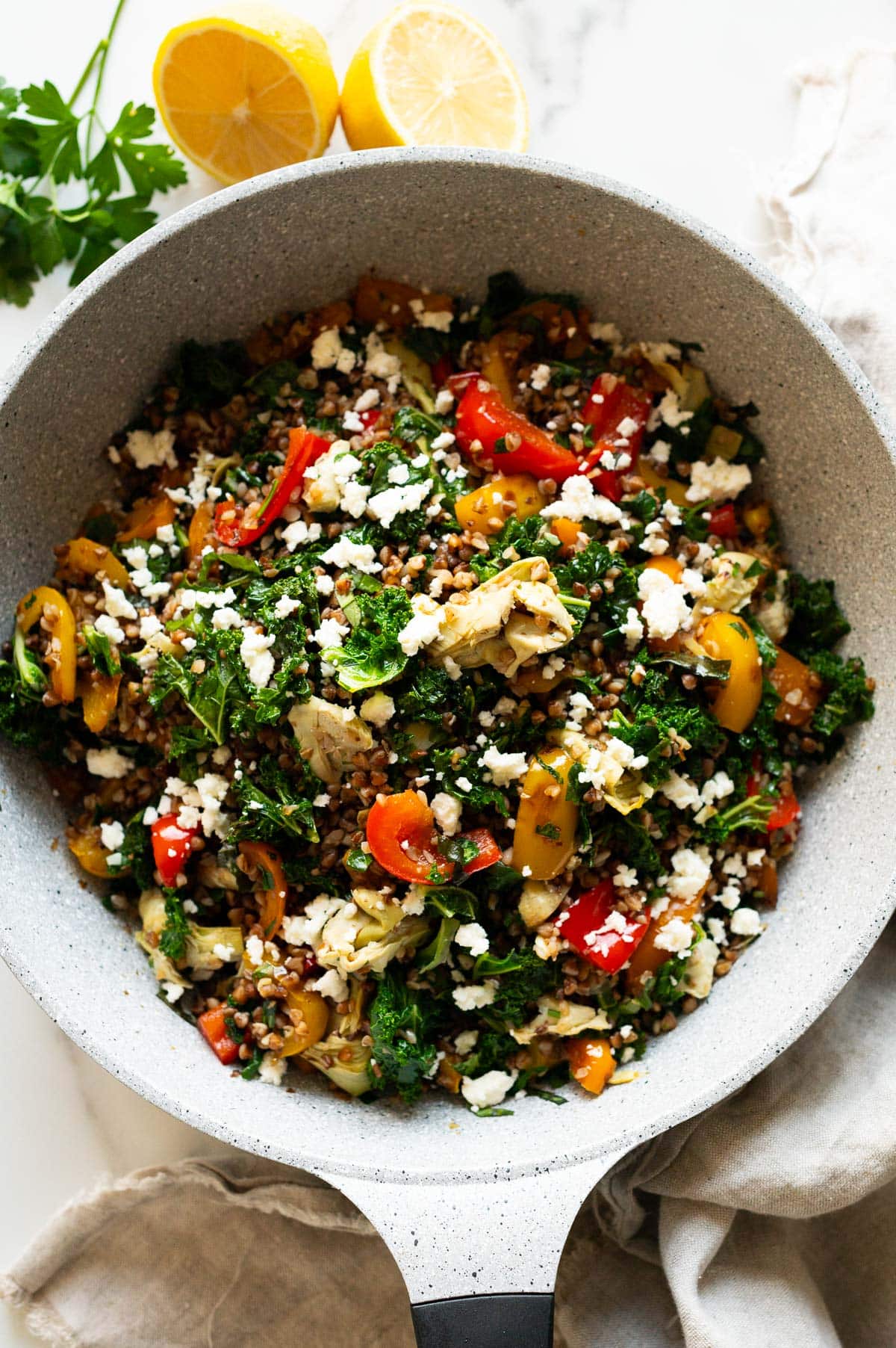 Buckwheat stir fry recipe with vegetables and feta in a skillet.