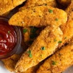 Air fryer chicken tenders with ketchup and parsley garnish.