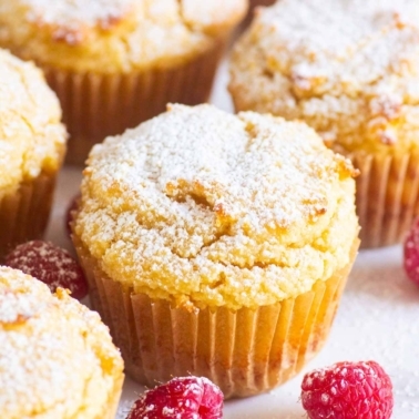 Almond flour yogurt muffins in paper liners dusted with sugar with fresh raspberries.