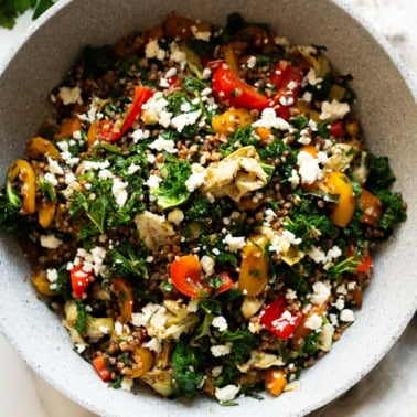 Buckwheat stir fry recipe with vegetables and feta in a skillet.