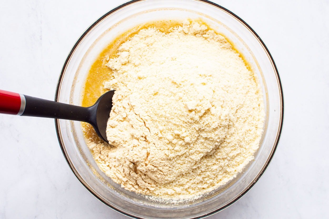 Almond flour being added to a bowl.