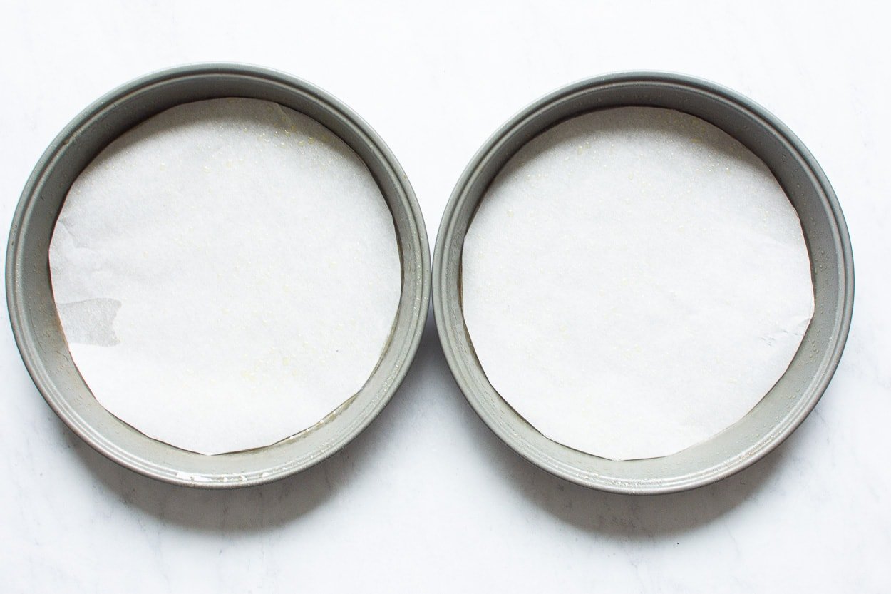 Two round cake pans lined with parchment paper.