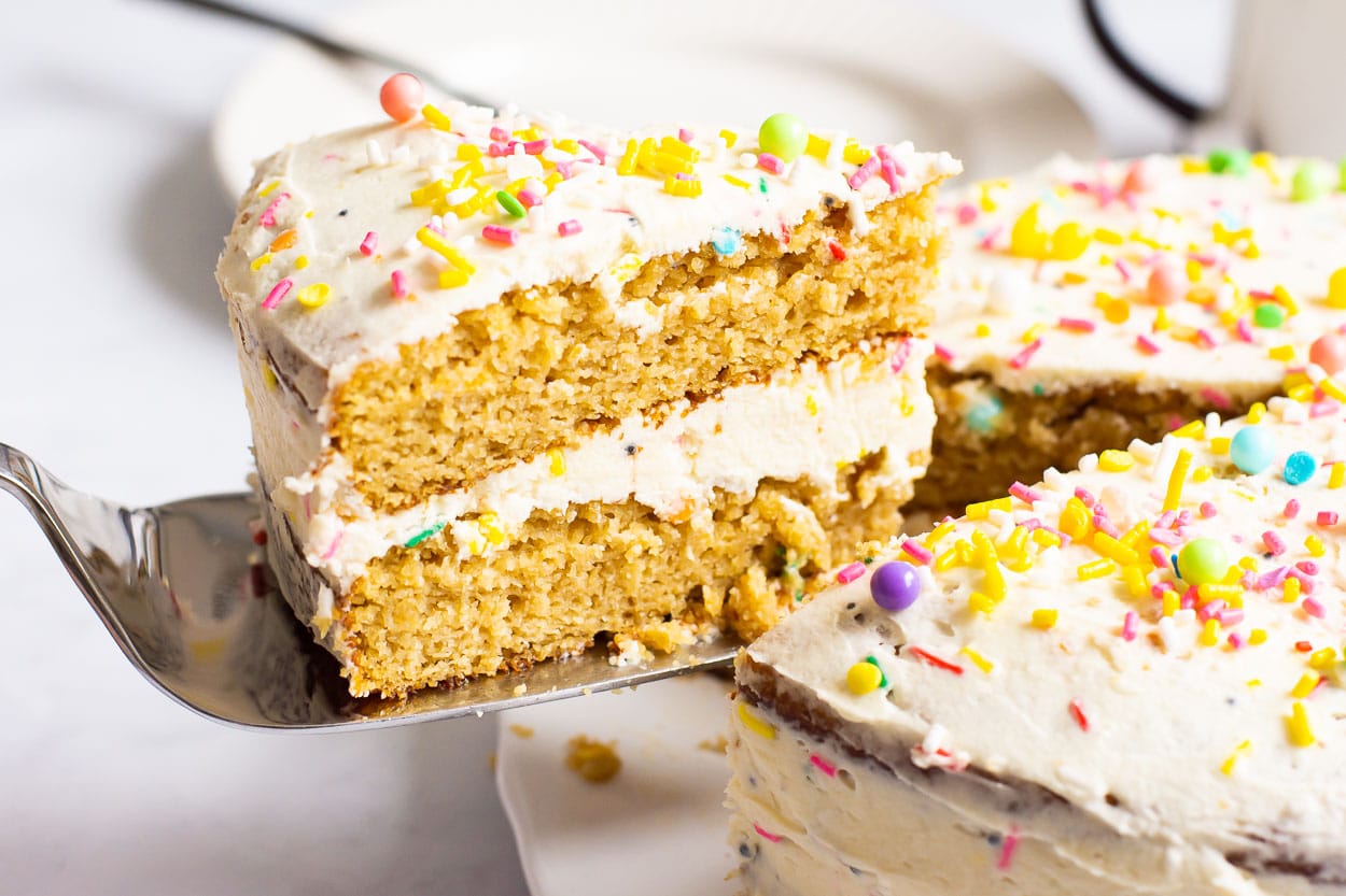 Healthy birthday cake with sprinkles slice on a cake server showing inside.