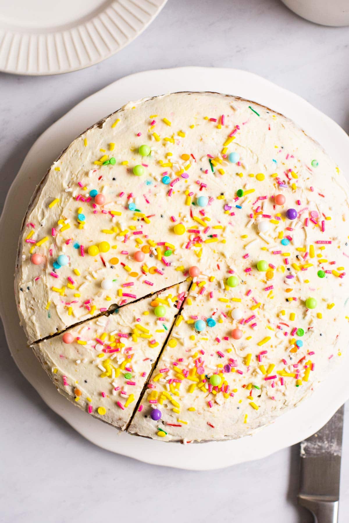 Looking down at a cake with sprinkles that has one piece sliced.