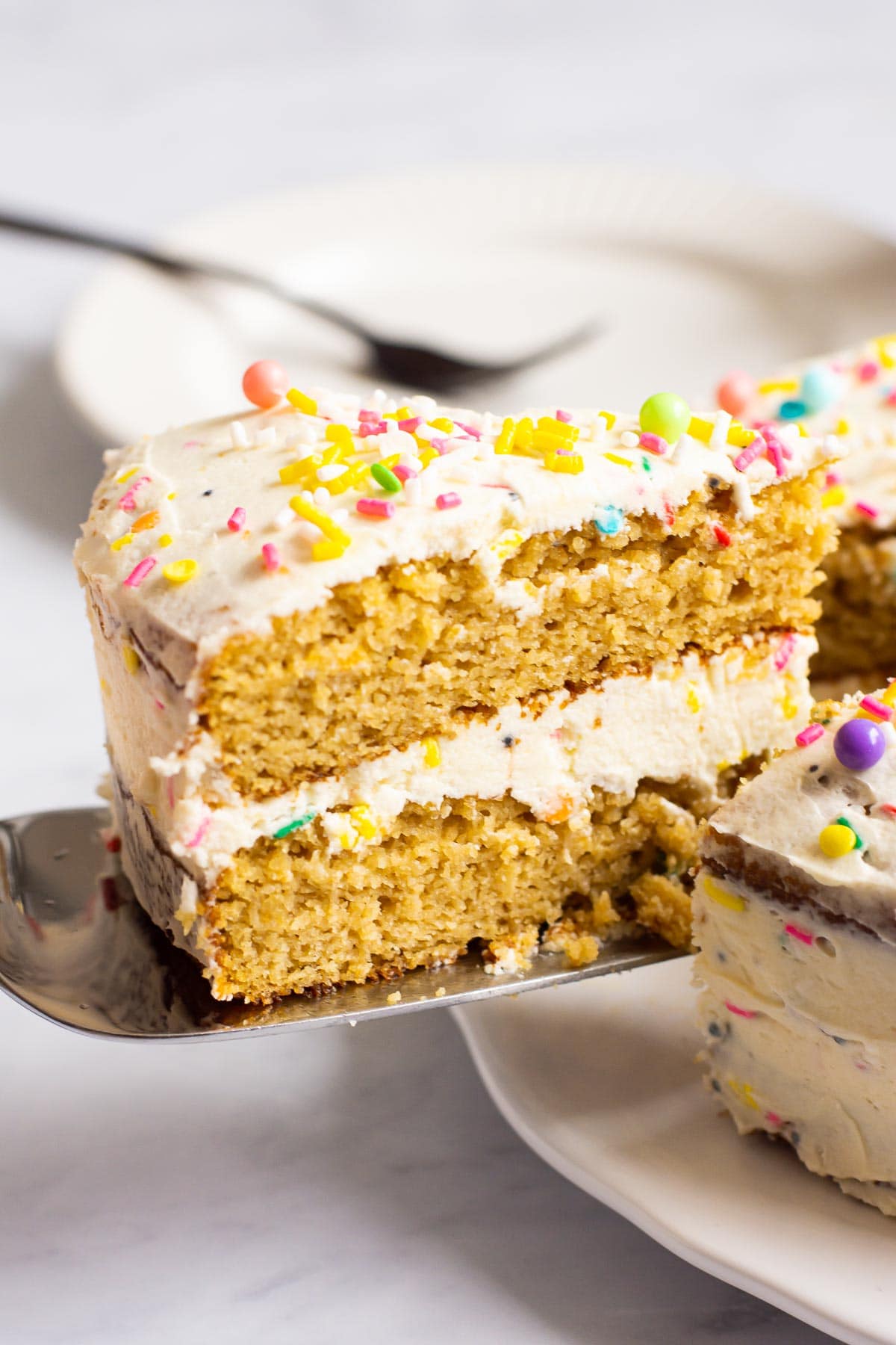 Healthy birthday cake with sprinkles being served with a silver cake server.
