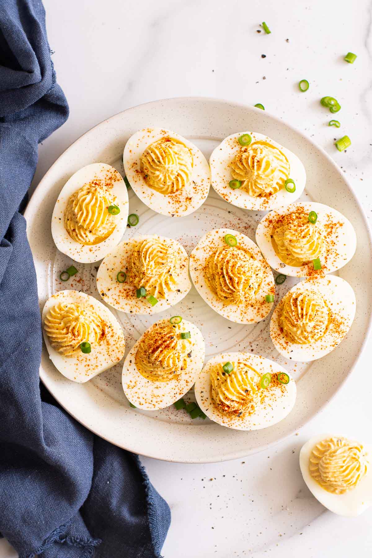 A plate of healthy deviled eggs with a blue linen.