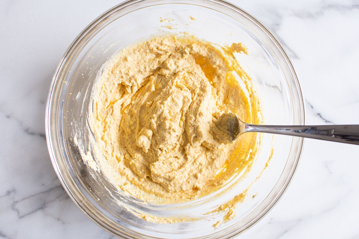 Egg yolk mixture in glass bowl with a fork.