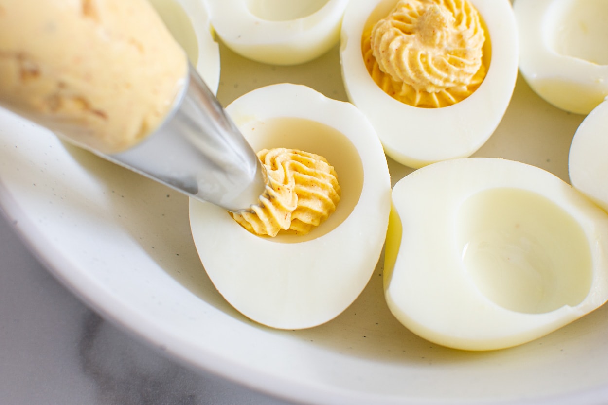 Filling deviled eggs with piping tip.