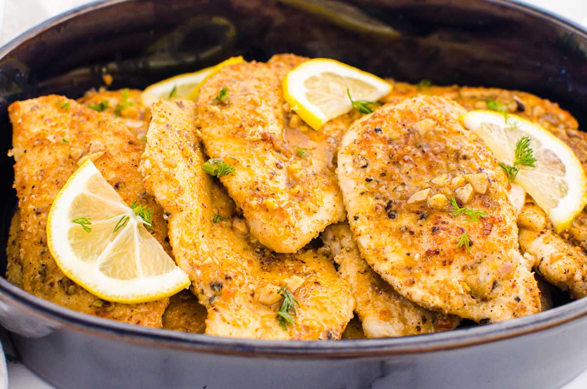 Lemon chicken with garlic butter sauce in baking dish.