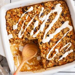 Carrot cake baked oatmeal in baking dish with serving spoon.