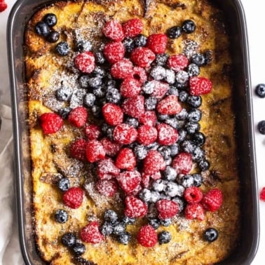 Healthy french toast casserole topped with mixed berries and icing sugar.