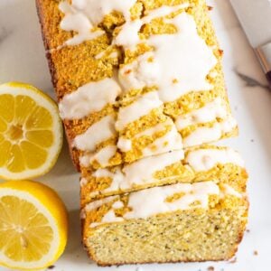 Healthy lemon poppy seed bread with glaze and fresh lemons.