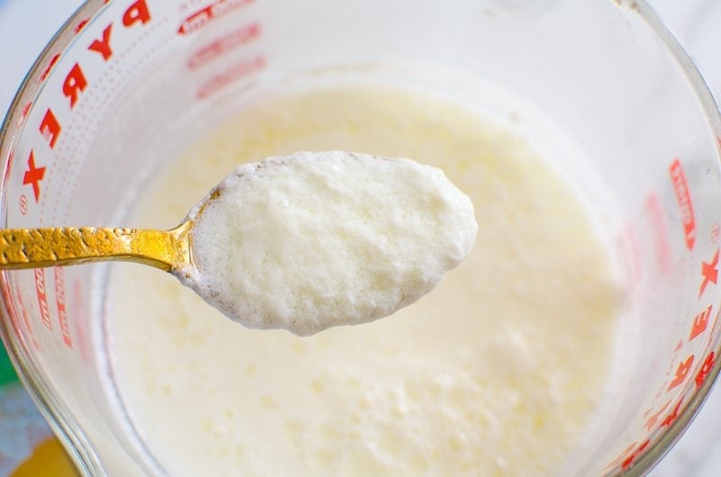 Sour milk on a spoon showing curdled texture.
