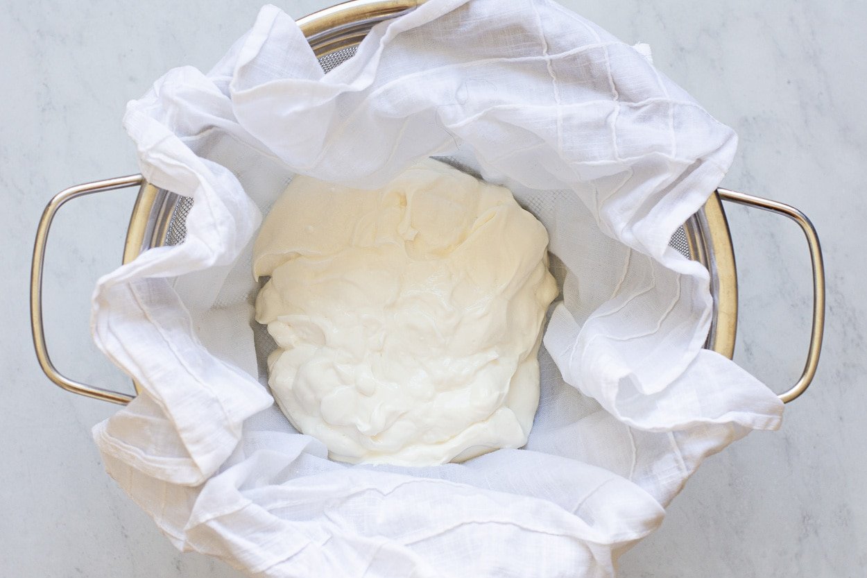 Straining Greek yogurt in a colander lined with linen towel. 