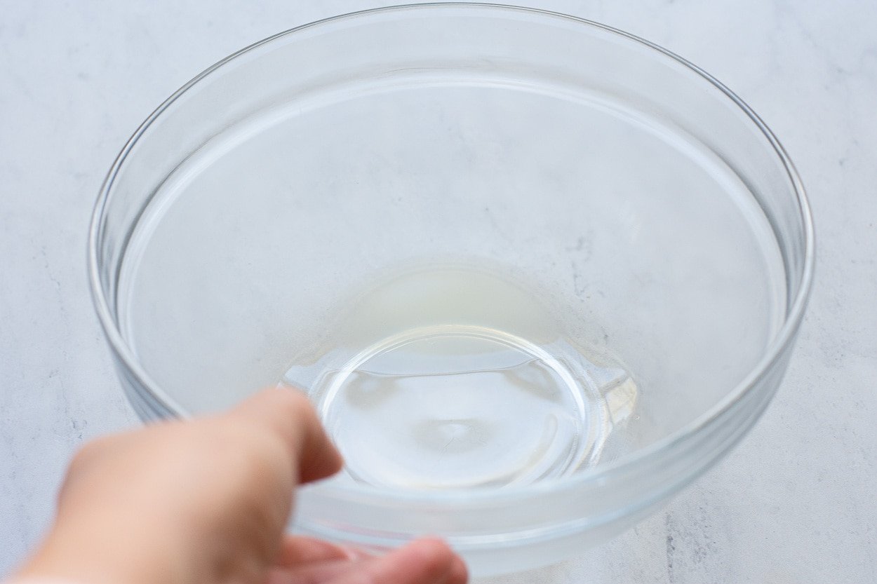 Whey liquid strained from Greek yogurt in glass bowl.