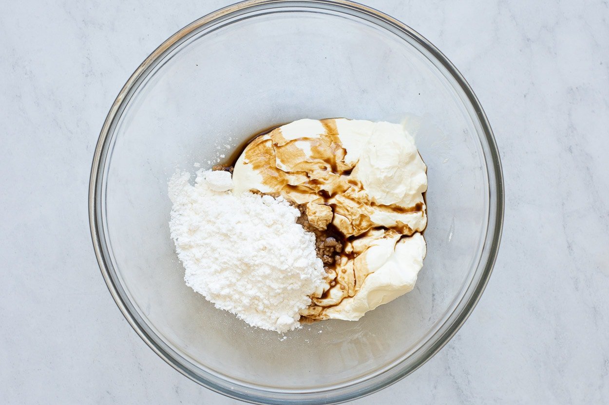 Powdered sugar, vanilla, Greek yogurt in bowl.