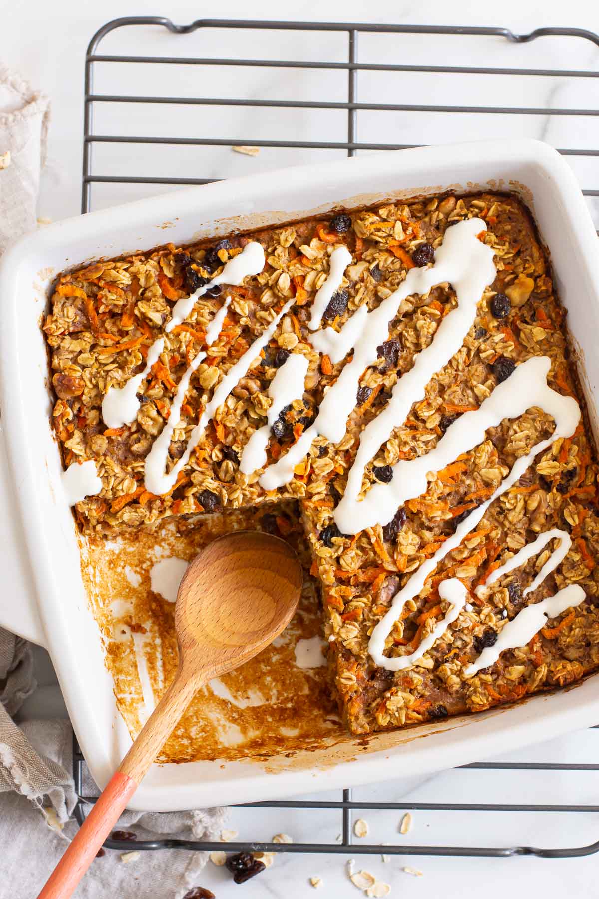 Healthy carrot cake baked oatmeal in baking dish on wire rack.