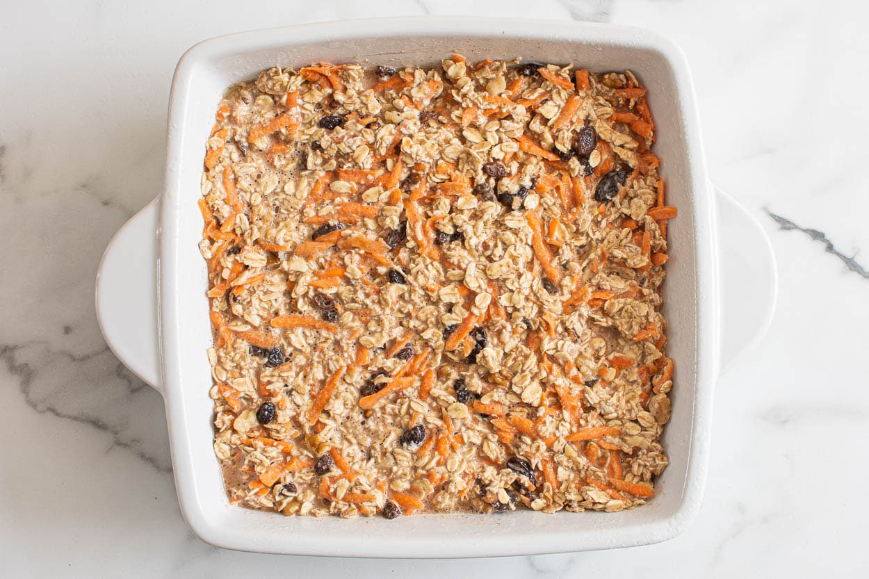 Unbaked carrot cake baked oatmeal in square white baking dish.