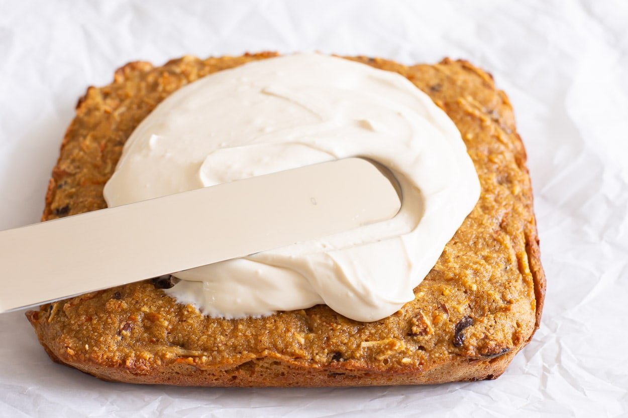 Healthy cream cheese frosting being spread onto bars.