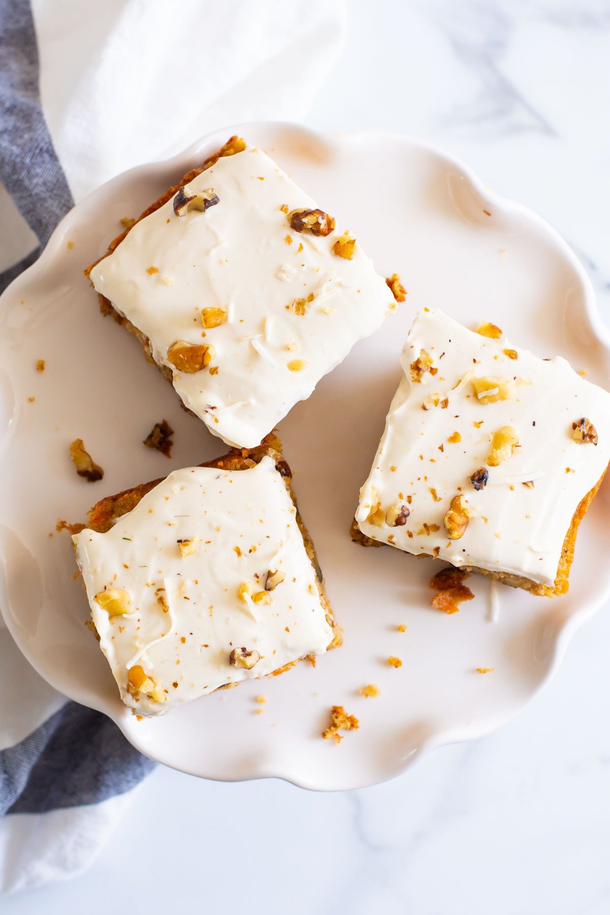 Looking down at three iced healthy carrot cake bars on a cake stand.