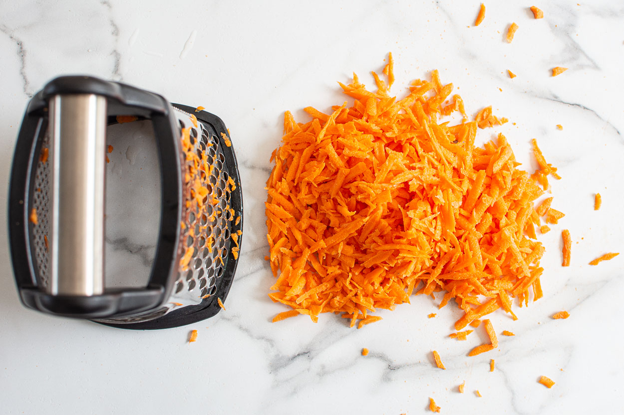 Pile of shredded carrots with box grater.