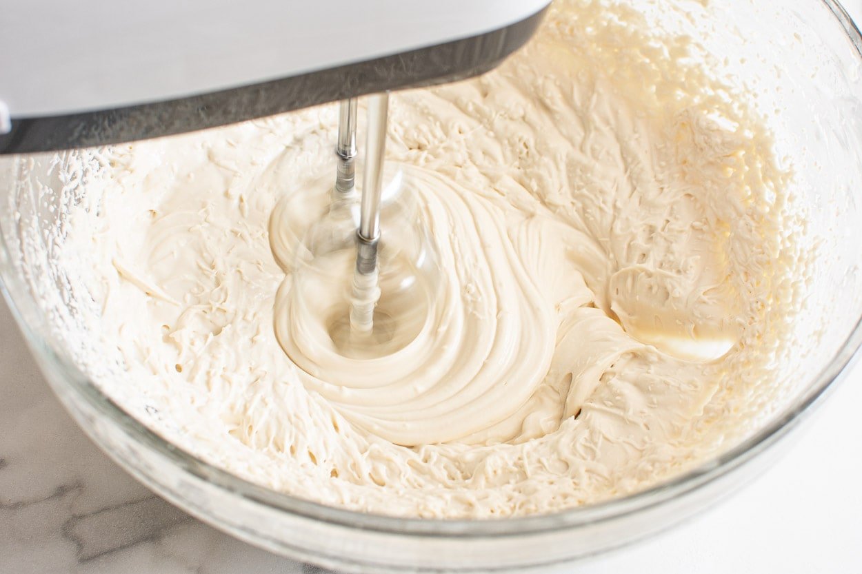 Electric mixer with beaters mixing bowl of frosting.