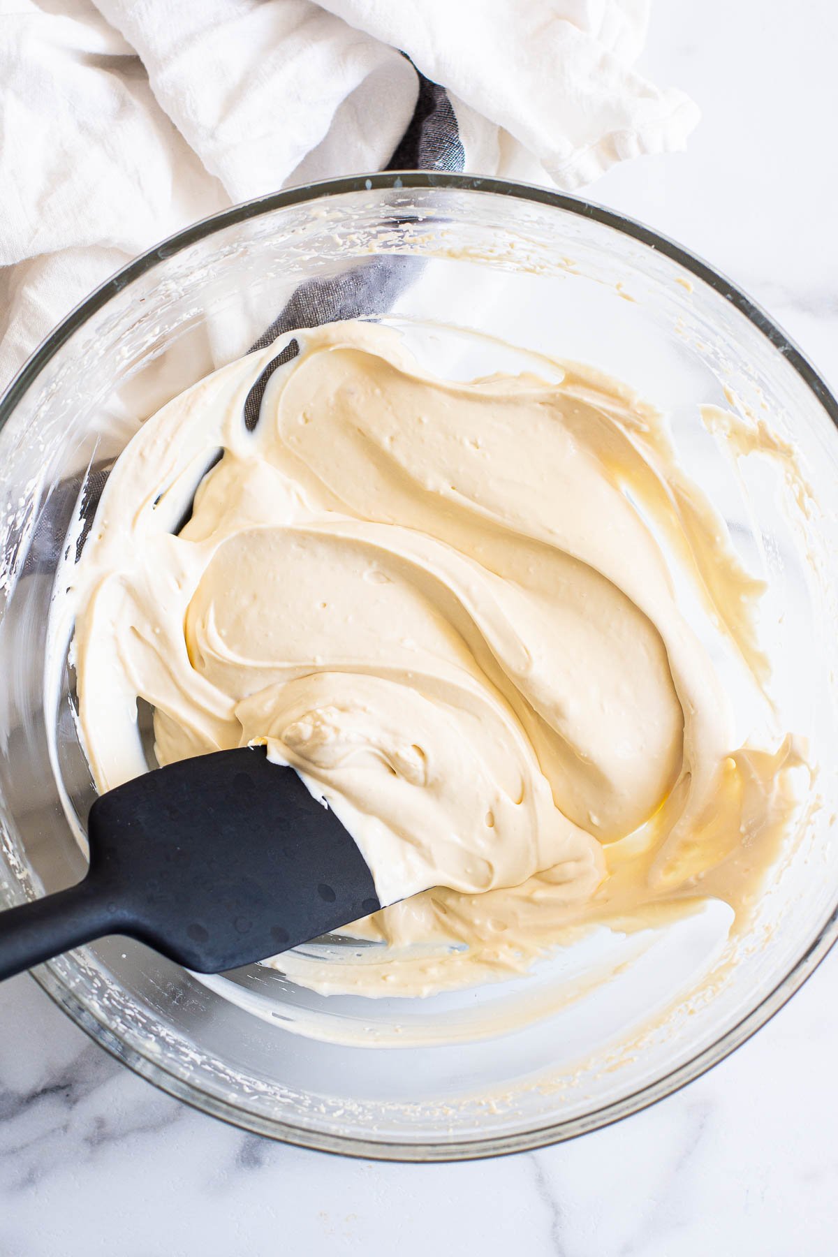 Healthy cream cheese frosting in glass bowl with spatula.