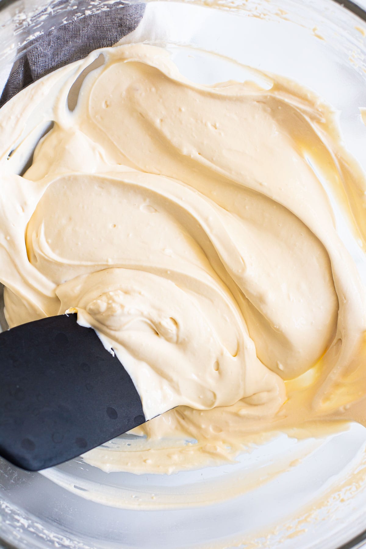 Healthy cream cheese frosting in a bowl with a black spatula.
