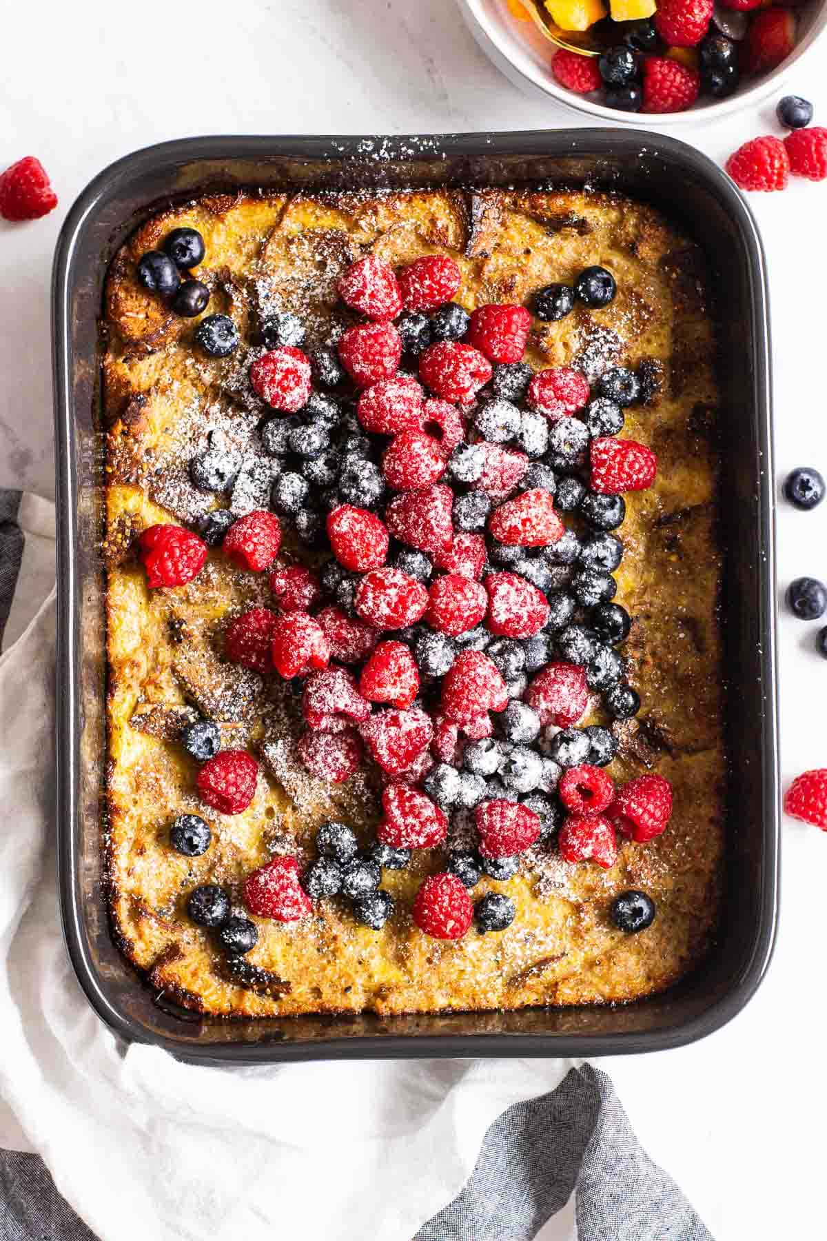 Healthy french toast casserole topped with fresh berries and icing sugar.