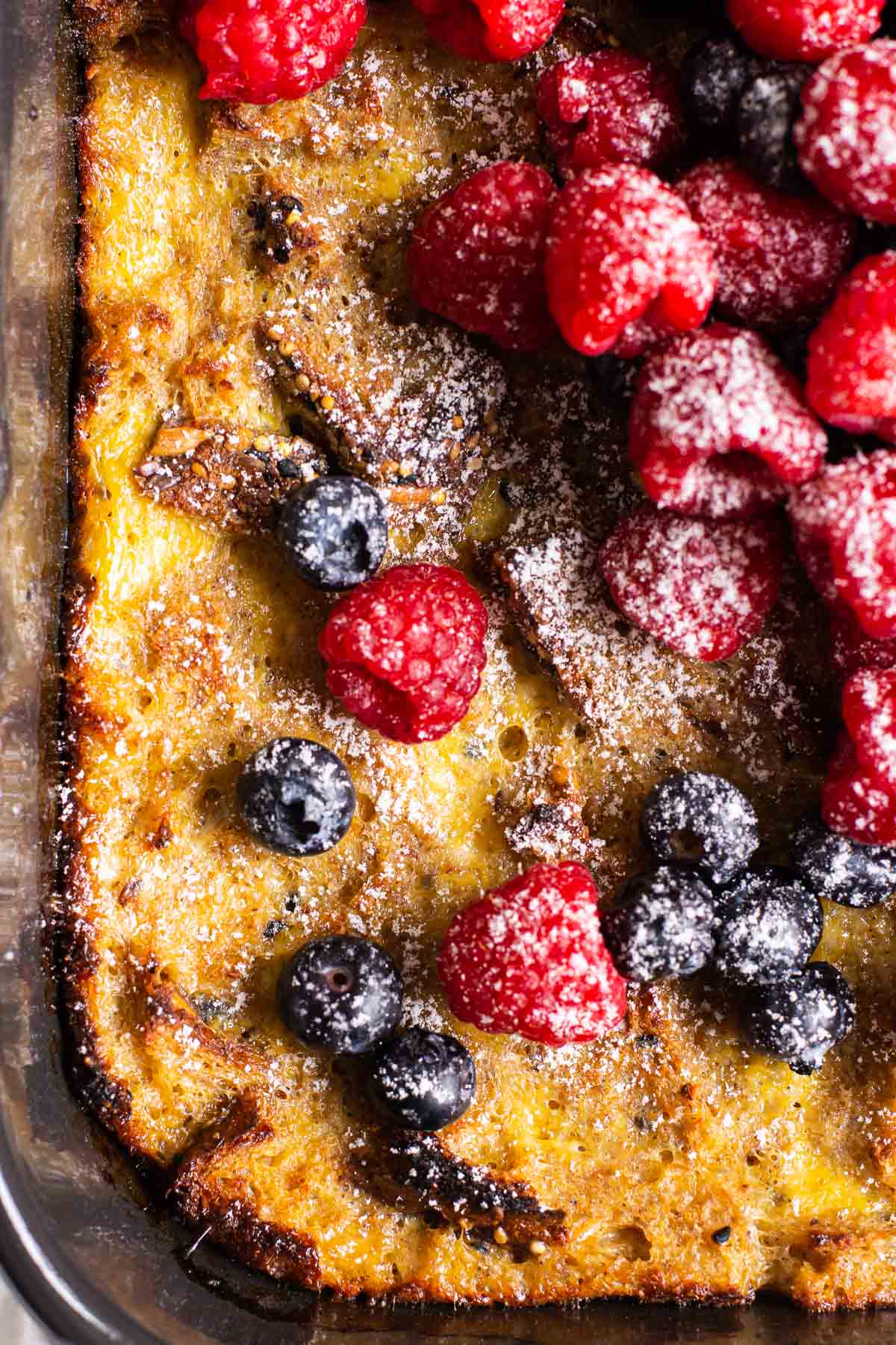 Close up of healthy french toast casserole with fresh berries and icing sugar.