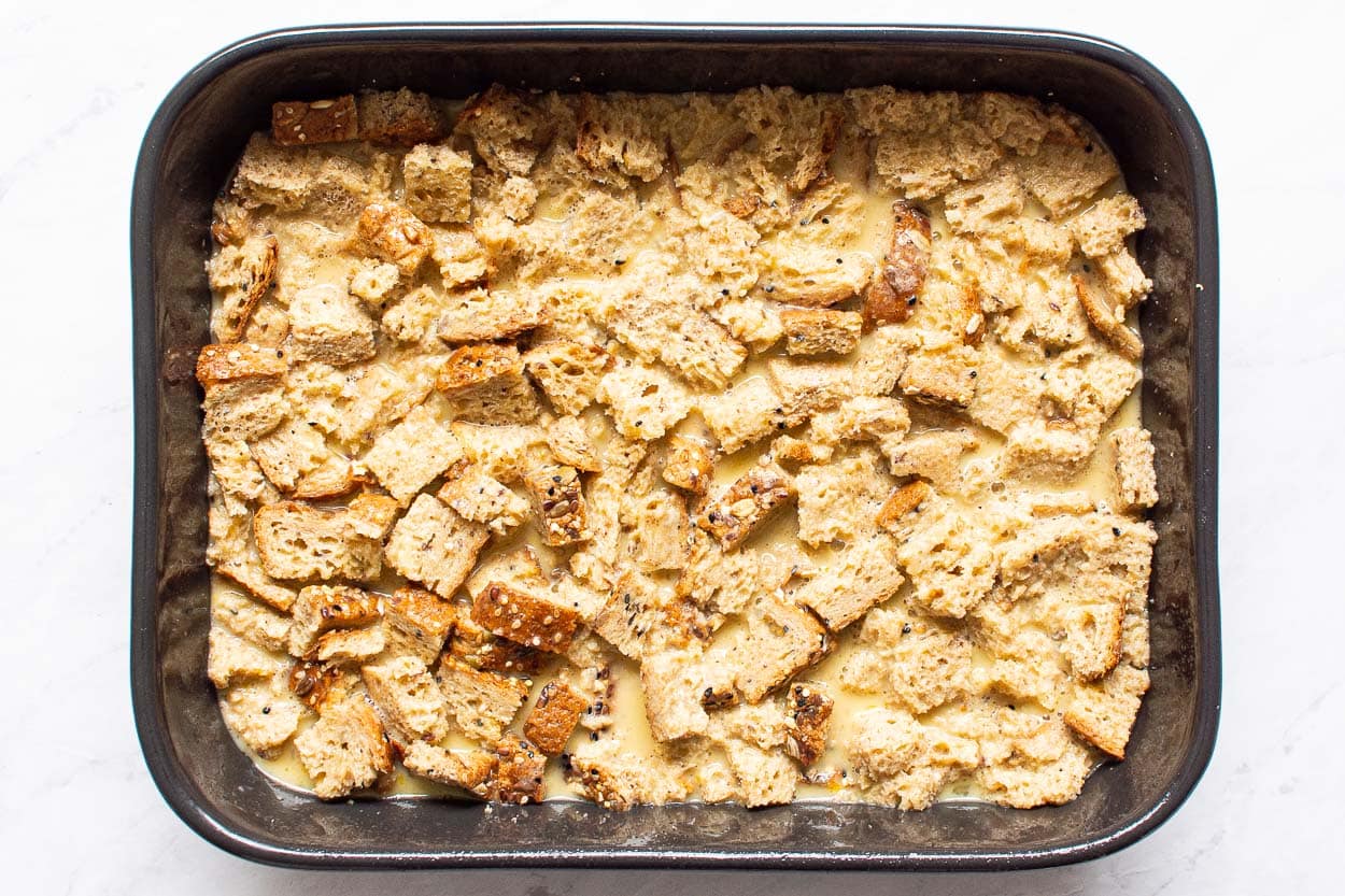 Egg mixture and whole grain bread cubes in baking dish.