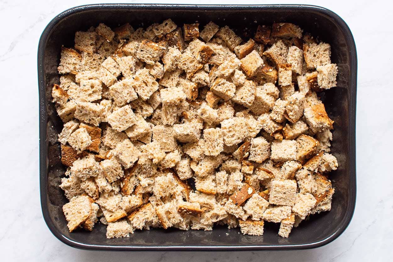 Whole grain bread cubes in baking dish.