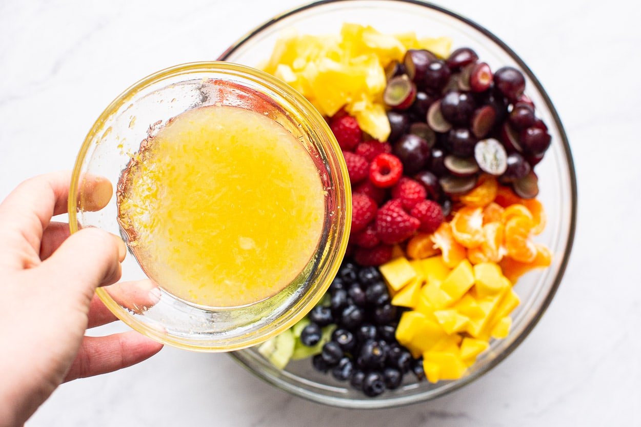 Dressing in bowl over fruit salad below.