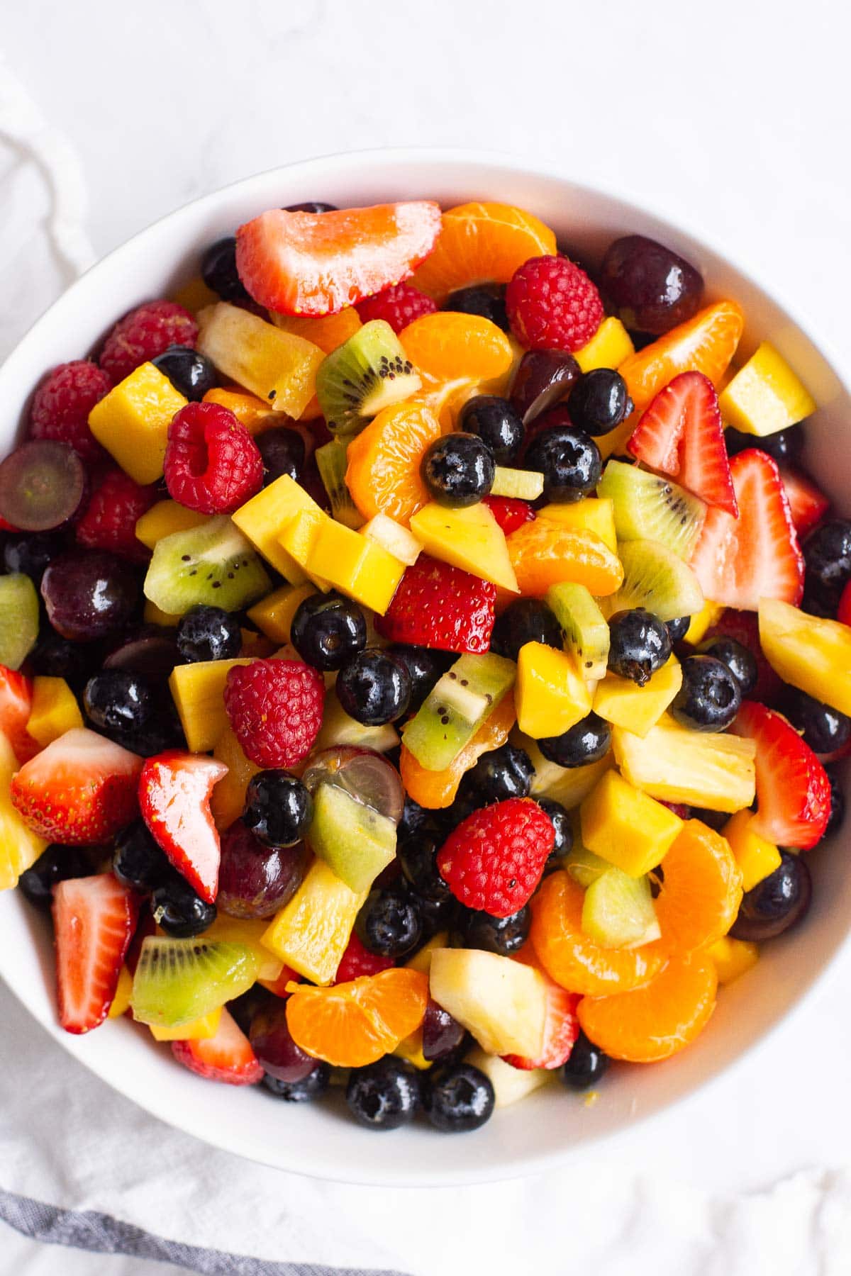 Healthy fruit salad with mandarins, kiwi, grapes and berries in a bowl.