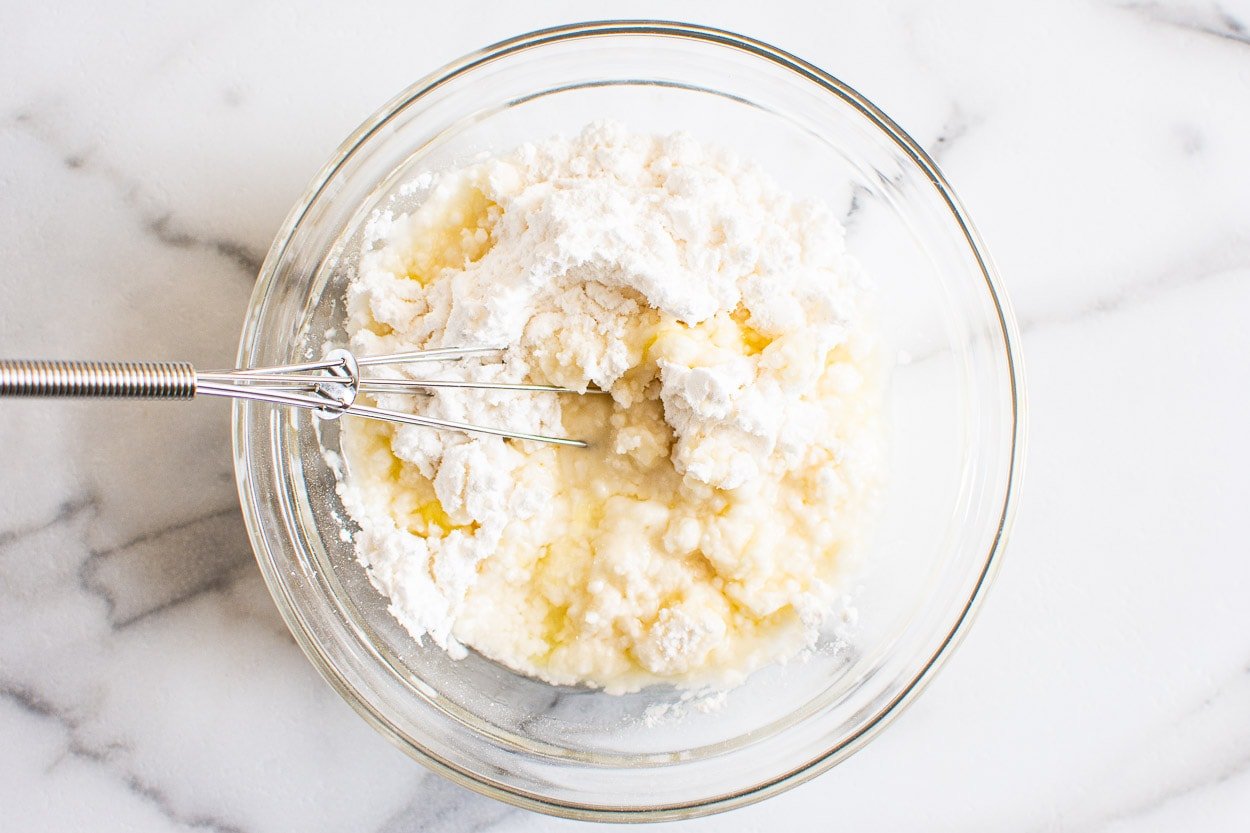 Powdered sugar and lemon juice with whisk in bowl.