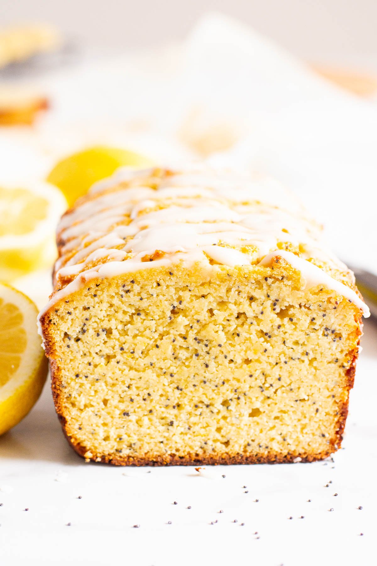 Loaf of healthy lemon poppy seed bread with glaze that has been sliced.