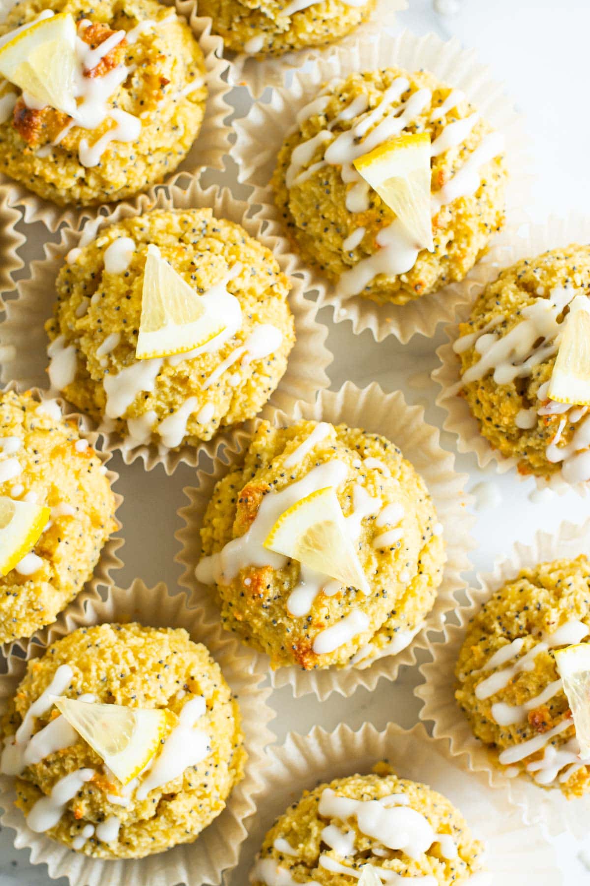 Looking down at healthy lemon poppy seed muffins with glaze and lemon slice.