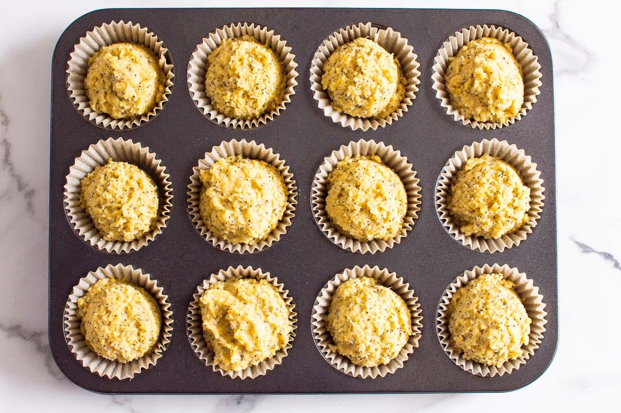 A muffin tin with muffin batter in parchment cups.