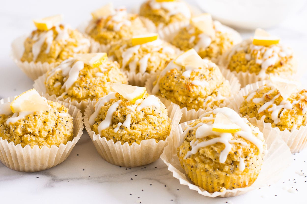 Healthy lemon poppy seed muffins with glaze and a slice of lemon on top.