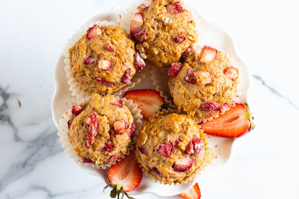 Looking down at five healthy strawberry muffins on a platter.