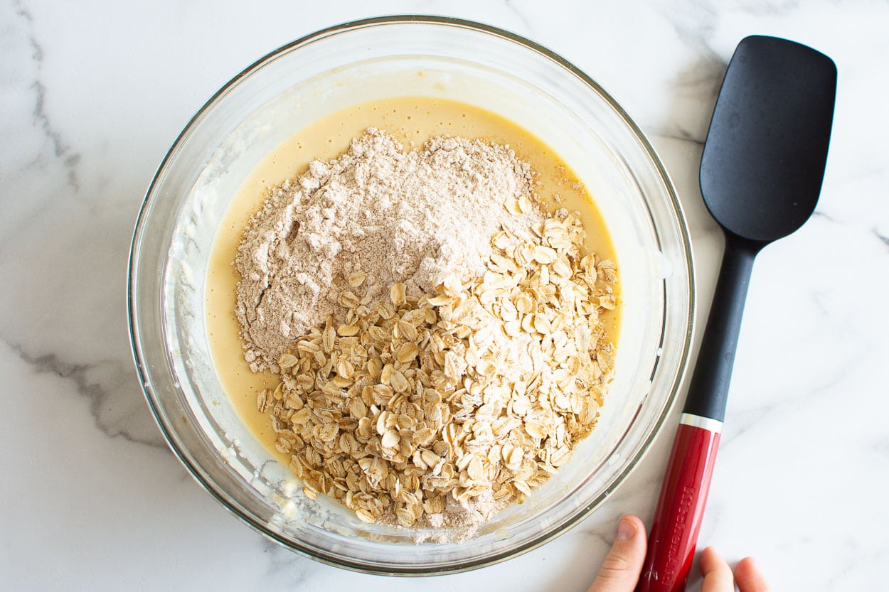 A bowl with flour, oats and liquid ingredients. 