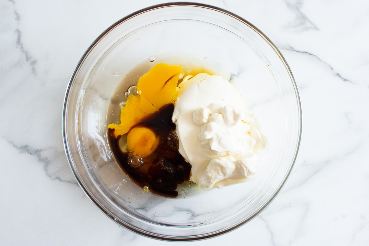 Eggs, maple syrup, vanilla, Greek yogurt in a bowl.