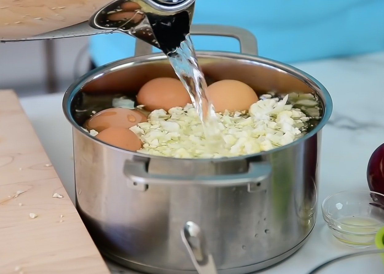 Pouring water into a pot with eggs and cauliflower.