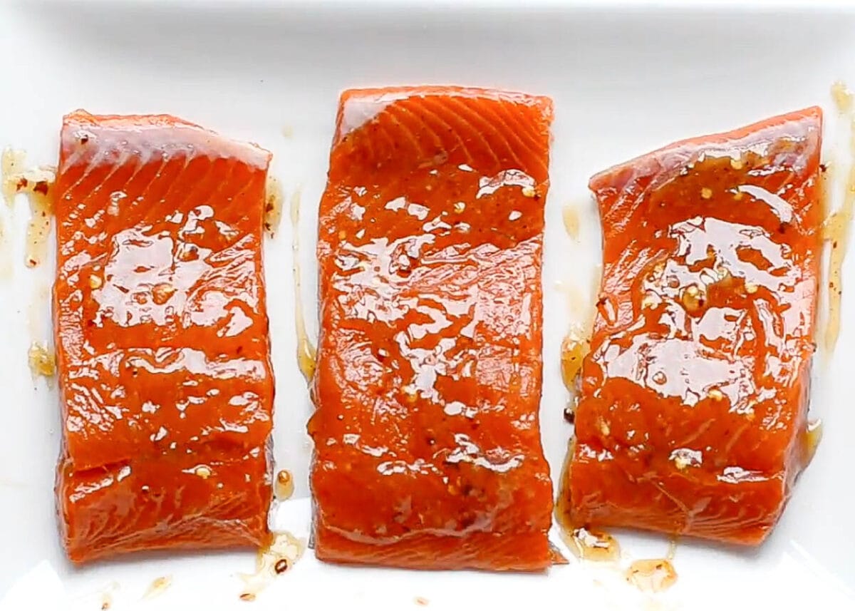 Coated in sweet chili sauce salmon fillets on white plate.