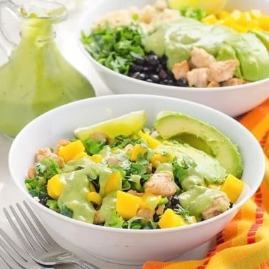 Chicken quinoa bowl with cilantro avocado dressing in white bowls.